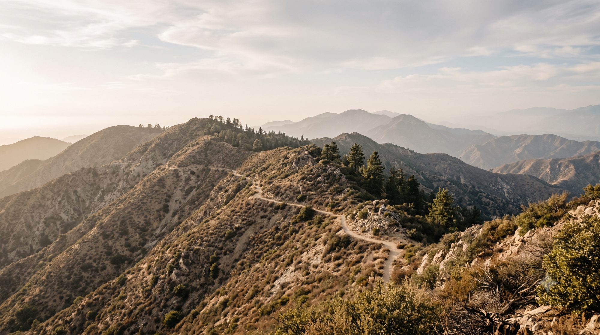 A dry chaparral ridgeline trail in the San Gabriel Mountains at golden hour, the Angeles Crest 100 course